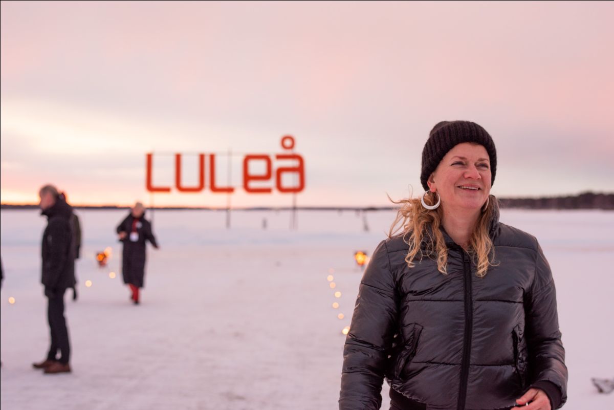 Bild på Lotta Rönström framför Luleå-skylt på isen